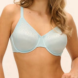 A woman modeling a light blue textured underwire bra against a plain beige studio background.