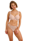 Woman wearing a beige bra and panties set on a white background