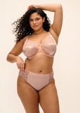 Woman wearing a pink bra and panties set on a beige background