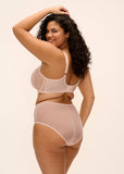Woman wearing a beige lingerie set against a plain background