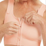 Woman wearing a peach-colored zip-up post op bra on a white background