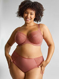 Woman wearing a pink bra and panties set against a plain background