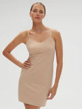 Woman wearing a beige slip dress against a plain background