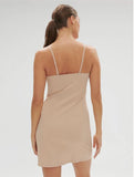 Woman wearing a beige slip dress against a plain background